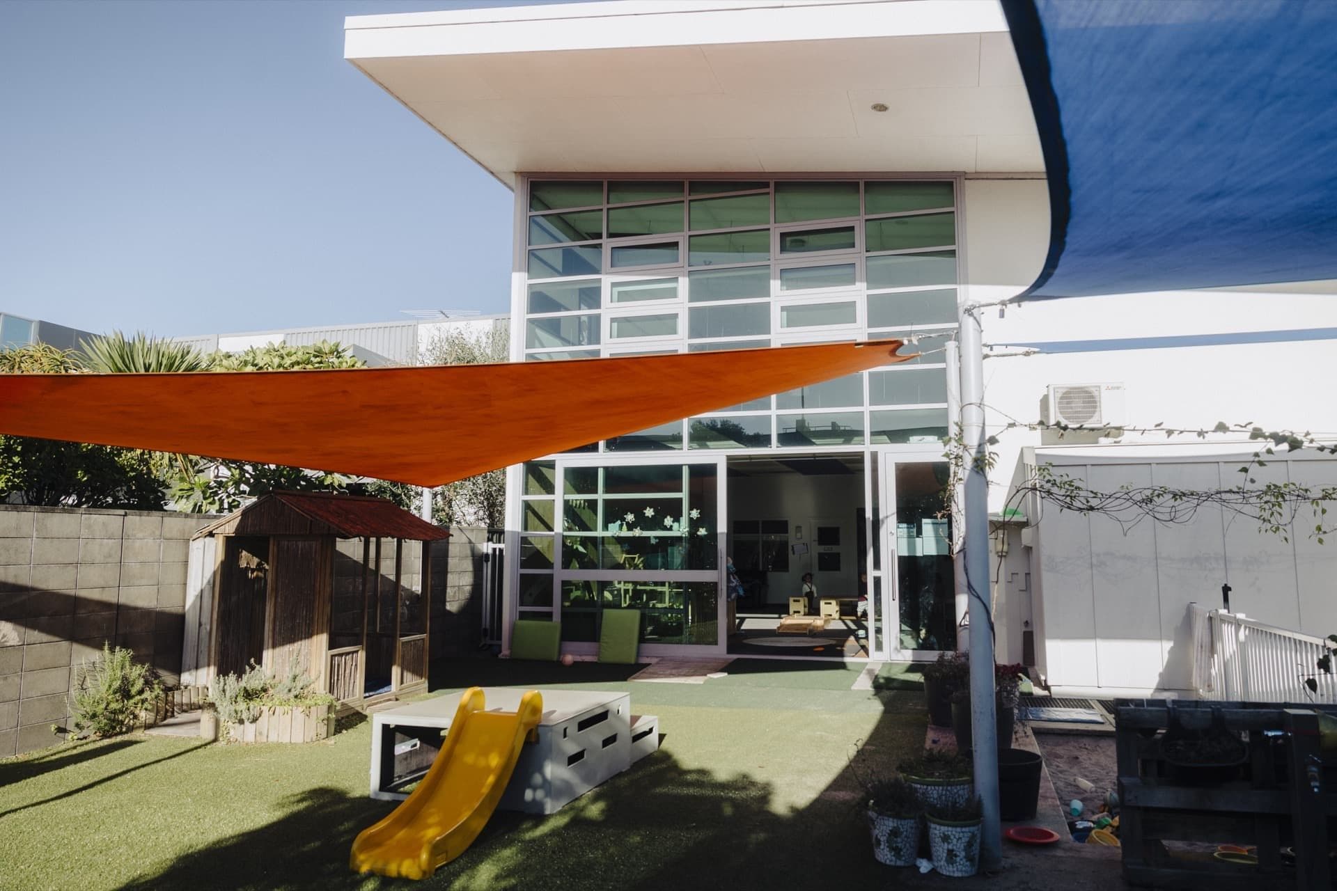Front entrance and outdoor play area at Triton Montessori Educare with shade sails and a slide