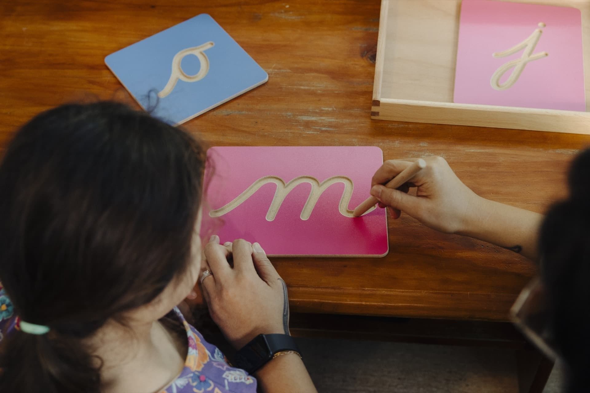 Close-up of hands tracing cursive Montessori sandpaper letters