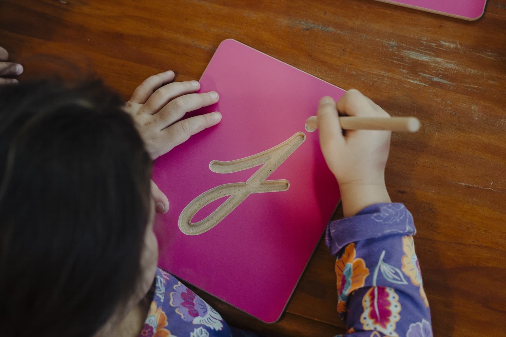Close-up of hands tracing cursive Montessori sandpaper letters