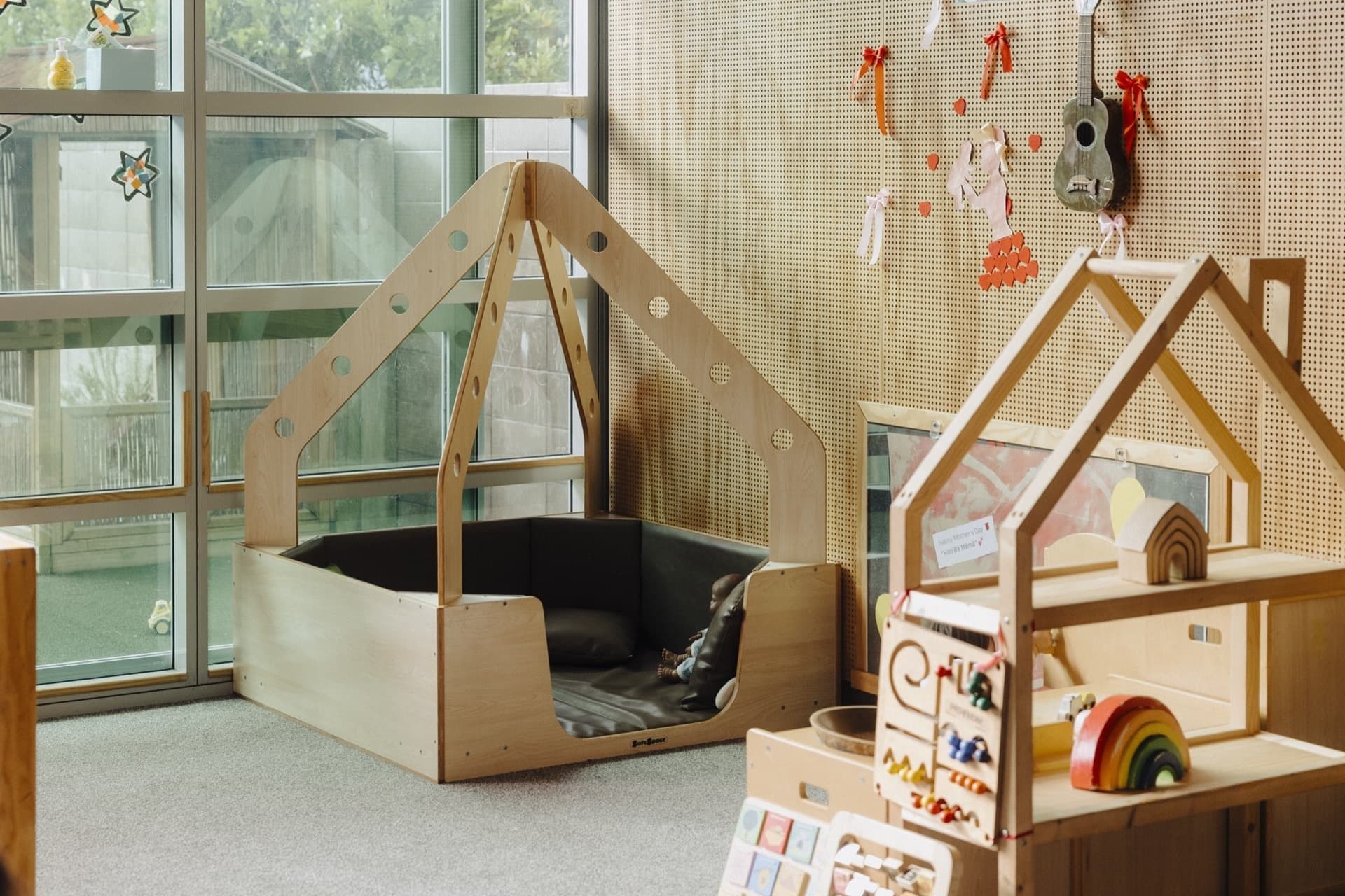 Infant room play space with a wooden climbing arch and low shelves at Triton Montessori Educare