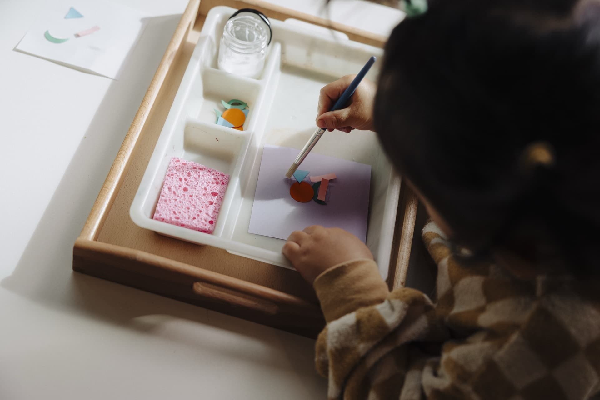 Child working with a Montessori practical life tray at a classroom table