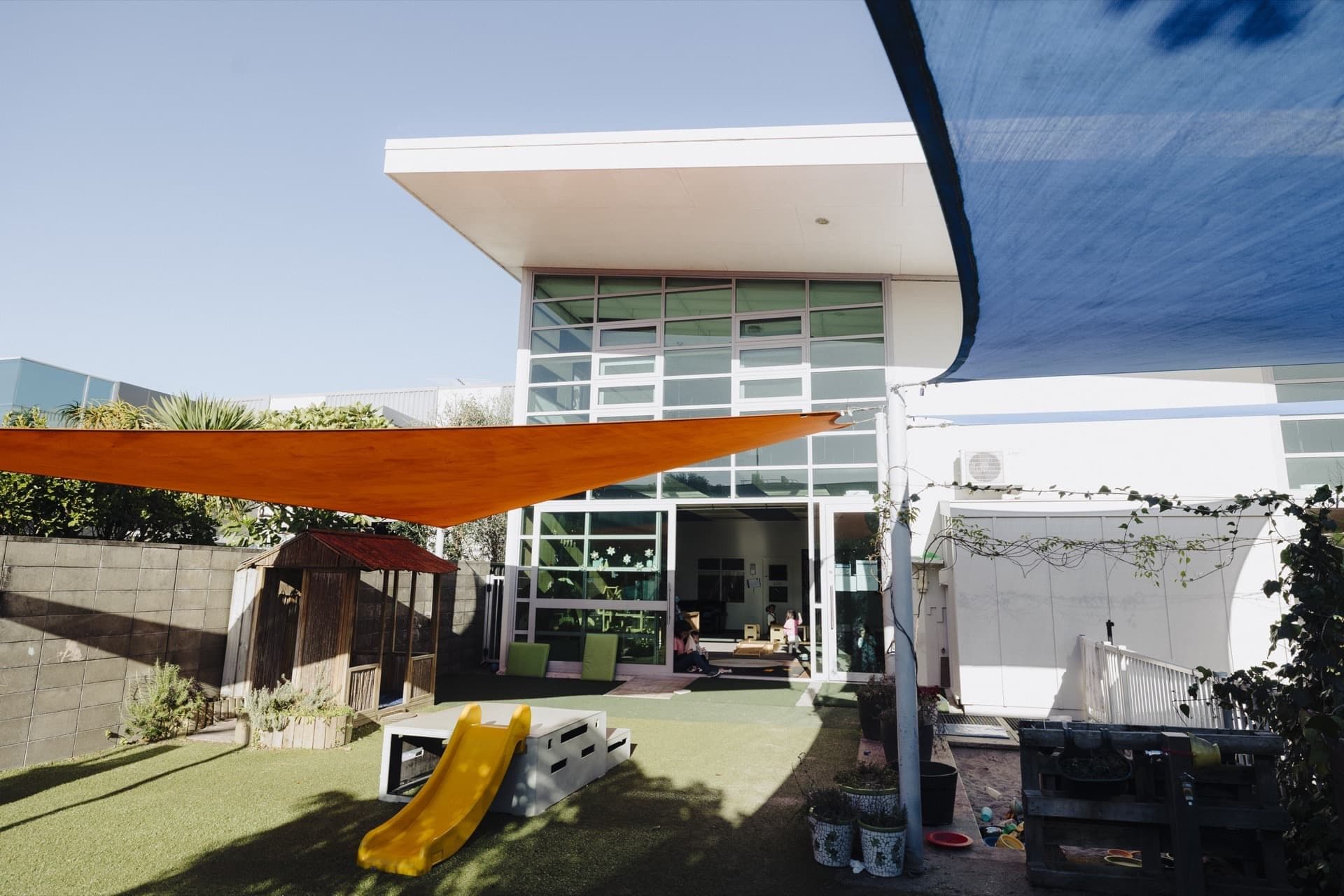 Front entrance and outdoor play area at Triton Montessori Educare with shade sails and a slide