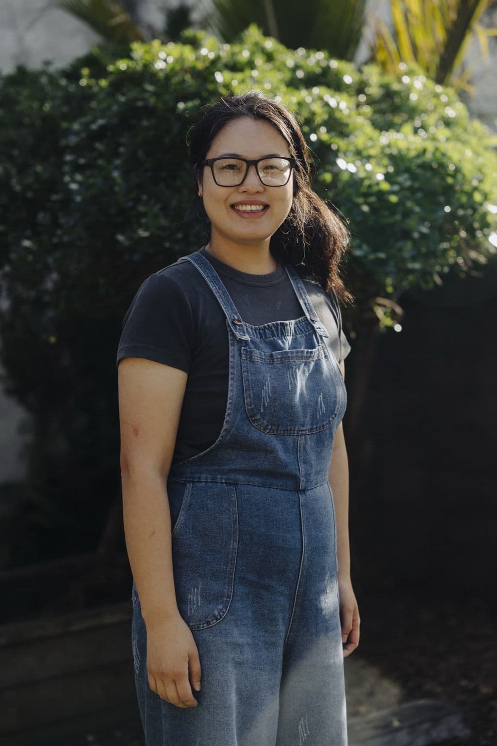 Smiling Triton Montessori team member in a denim pinafore outdoors