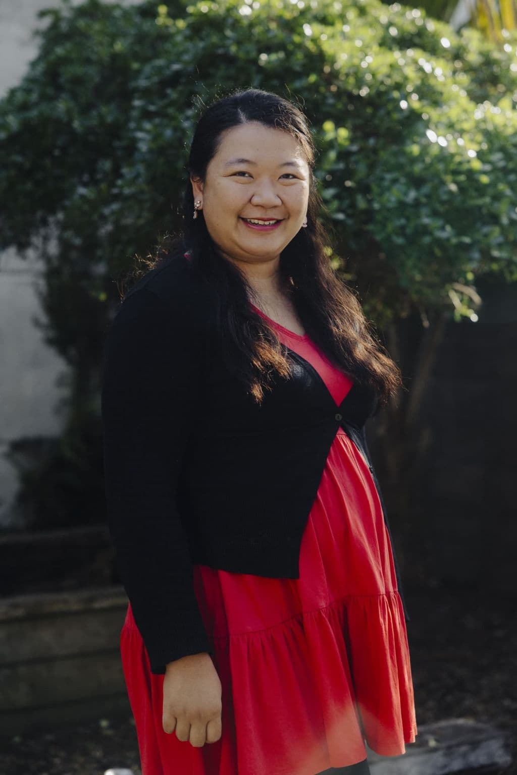 Triton Montessori team member portrait outdoors in a black cardigan and red dress