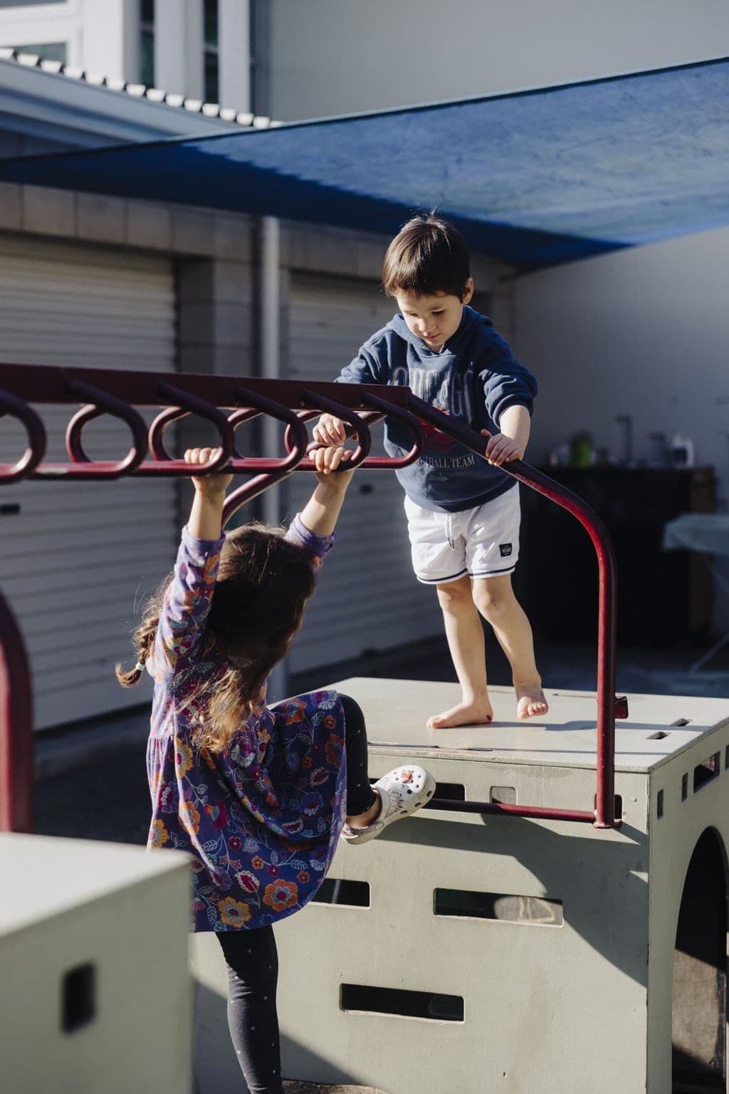 Children climbing and balancing on outdoor playground equipment at Triton Montessori Educare