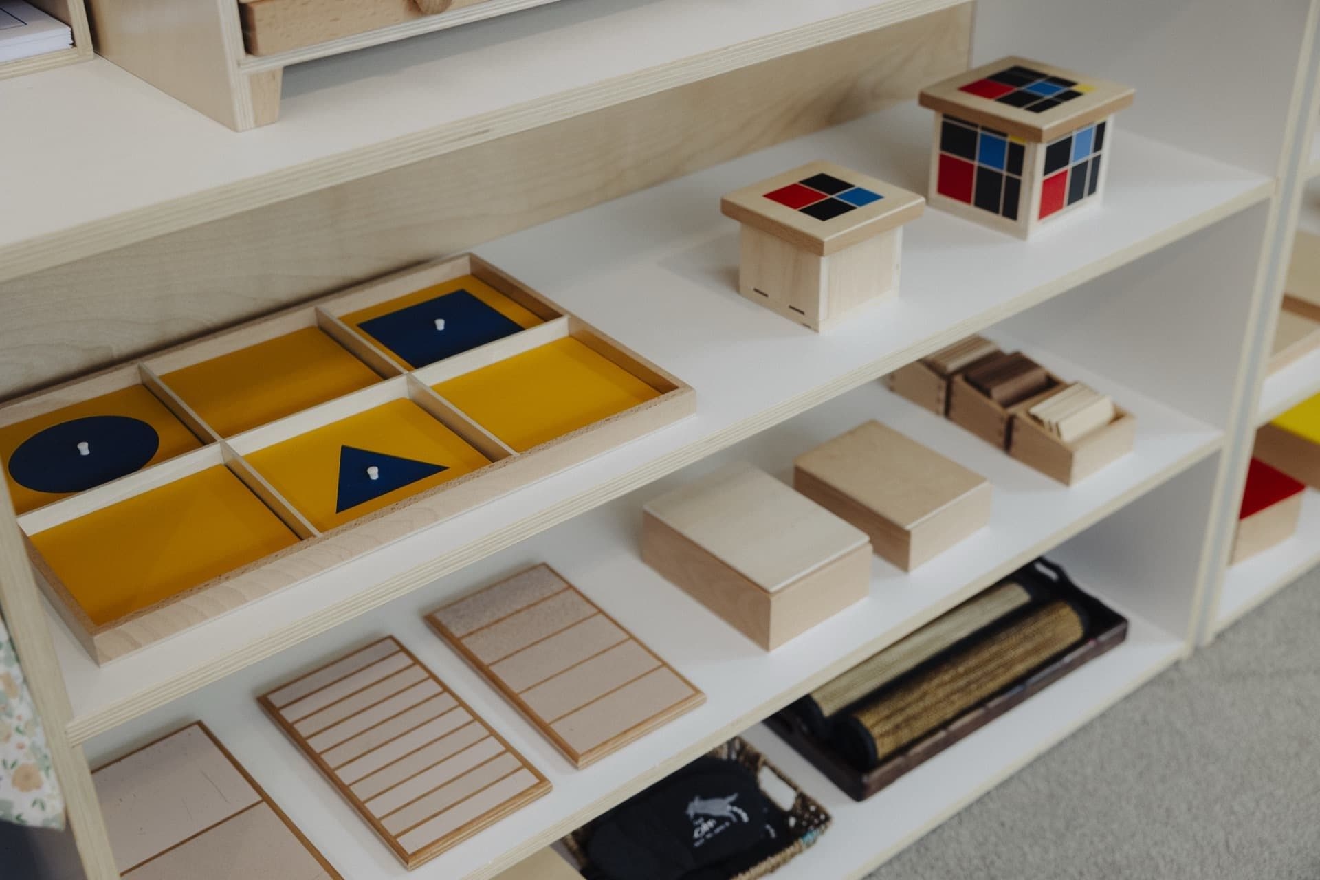 Montessori maths and sensorial materials displayed on a low classroom shelf